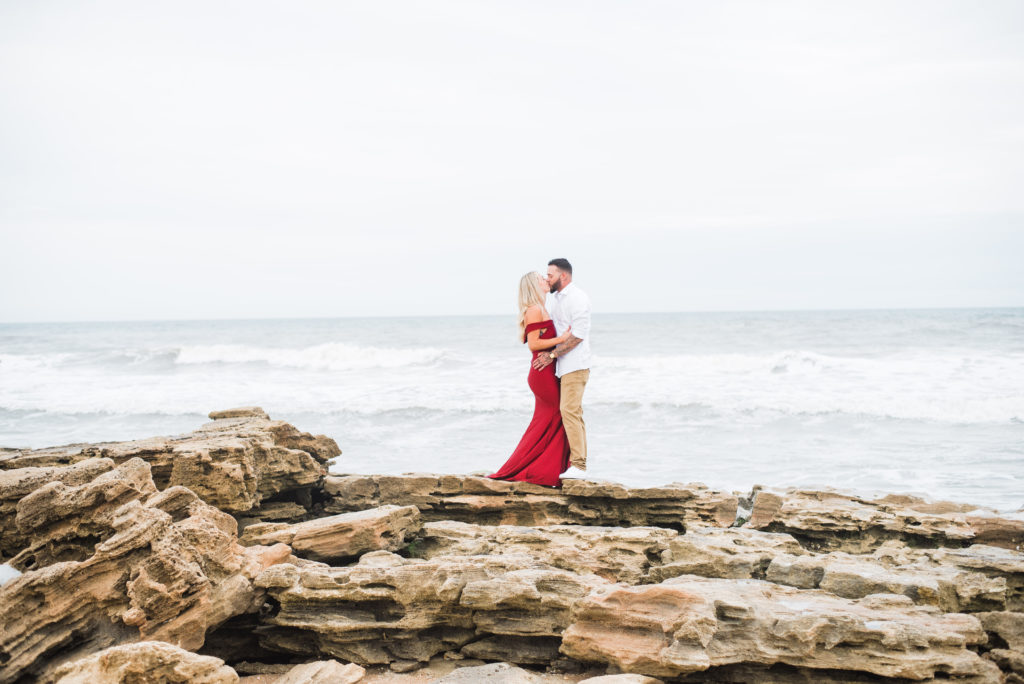Couple kisses while standing on rocks on the beach at Washington Oaks Beach in Palm Coast Florida
photo by Chabeli Woolsey of Black Tie & Co www.btcweddings.com