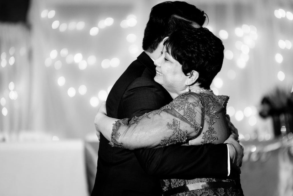 Black and white photo of mother hugging son during Groom and Mother of the groom dance 
Alachua Woman's Club in Florida 
Photo by: Black Tie & Co. (www.btcweddings.com)